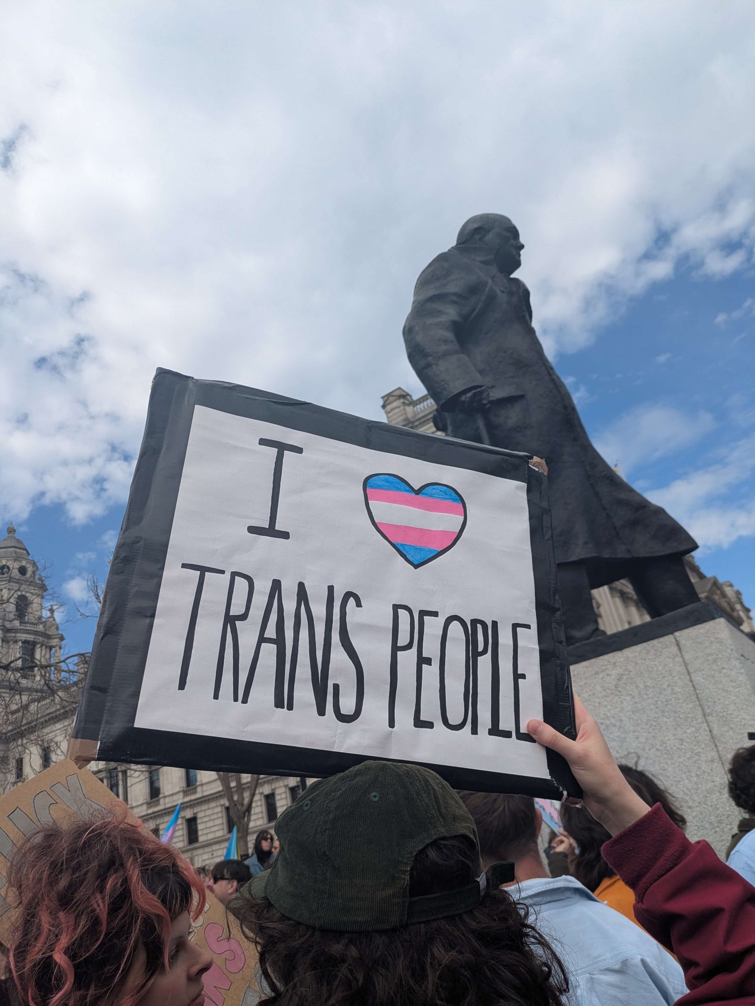 A heartfelt transgender support sign being held up during a protest for transgender rights.